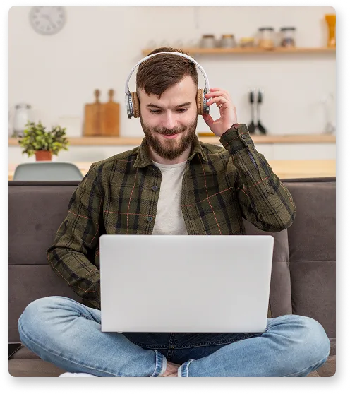 Persona con auriculares trabajando con un portátil en el sofá