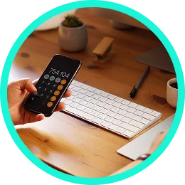 Manos con un móvil, una calculadora y un teclado sobre una mesa de trabajo