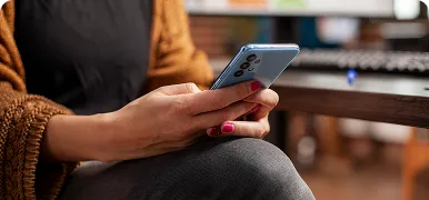 Mujer usando un smartphone sentada ante su ordenador