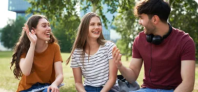 Tres jóvenes charlando y riendo en un parque