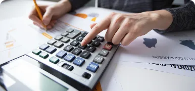 Persona sumando con una calculadora sobre documentos de facturación
